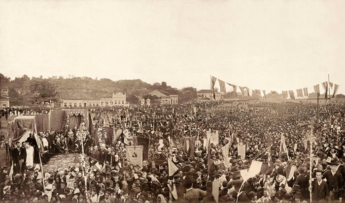 A revolta do escritor Lima Barreto contra o racismo Publicado por Fernando do Valle ×04/08/2015 às 11:14 Ainda estudante da Escola Politécnica do Rio de Janeiro, onde entrou em março de 1897, o escritor mulato Lima Barreto desiste de participar de uma estudanta, ato de rebeldia dos alunos da escola de elite. Consciente do racismo, Lima explica em conversa com um colega o motivo que o levou a desistir de pular o muro em companhia de seus colegas para assistir a uma montagem da ópera Aída de Verdi no Teatro Lírico: “Todos haviam topado a estudantada. Todos, menos Lima Barreto. Este não tivera a coragem de pular o muro. Depois do ensaio geral, Nicolao Ciancio teve de ir sozinho para casa — a pensão de Madame Parisot. E ali chegando, cantarolando, como bom italiano, os últimos trechos de Aída, encontrou o amigo deitado, lendo. O diálogo que se seguiu e vai adiante transcrito foi reconstituído pelo próprio Nicolao Ciancio. Ei-lo sem alteração de uma vírgula: — Por que você não veio? — Para não ser preso como ladrão de galinha! — ?! — Sim, preto que salta muros de noite só pode ser ladrão de galinhas! — E nós, não saltamos? — Ah! Vocês, brancos, eram ‘rapazes da Politécnica’. Eram ‘acadêmicos’. Fizeram uma ‘estudantada’… Mas, eu? Pobre de mim. Um pretinho. Era seguro logo pela polícia. Seria o único a ir preso”. (extraído do livro A Vida de Lima Barreto, de Francisco de Assis Barbosa) lima barreto racismo O escritor Lima Barreto pelo desenhista Cássio Loredano Afonso Henriques nasceu numa sexta-feira 13, a de maio de 1881, exatos 7 anos antes da abolição da escravatura, pobre, negro e alcoólatra, sofreu na pele as agruras do preconceito dos literatos, acadêmicos e jornalistas. Mas não se fazia de rogada, já na Politécnica, Lima escreve ácidos artigos na revista universitária A Lanterna, onde não poupa os vaidosos professores sob o pseudônimo de “Momento de Inércia”. Em seu diário íntimo, Lima frequentemente desabafava sempre o mesmo como um mantra: “é triste não ser branco”. Da sua revolta, nasceu uma literatura voltada para os personagens do subúrbio. Também praticou um jornalismo de resistência como na pequena Revista Floreal. No primeiro número da revista, Lima escreve que a publicação era “contra o formulário de regras de toda sorte, que nos comprimem de modo tão insólito no momento atual”. O primeiro número da revista vendeu apenas 38 exemplares, a Floreal não passou do quarto número. Foi ali que Lima publicou trechos de uma de suas obras mais contundentes, Recordações do Escrivão Isaías Caminha (1909), que narras as agruras de um jornalista negro e pobre no início de carreira. O livro é brutal, um grito contra a hipocrisia e um ataque aos medalhões da imprensa. Sem dúvida, o livro foi baseado na experiência de Lima no jornal Correio da Manhã. Antes do Correio, em 1903, Lima teve uma péssima experiência na Revista de Época, onde se viu obrigado a tecer loas a alguns políticos, pediu demissão. Dois anos depois, a partir de abril, escreve reportagens para o Correio da Manhã. Saiba mais sobre o livro Recordações do Escrivão Isaías Caminha. lima barreto biografia Montagem com fotos de Lima Barreto (fonte: Jornal da Unicamp) “Não obedeço a teorias de higiene mental, social, moral, estética, de espécie alguma. O que tenho são implicâncias parvas; e só isso. Implico com três ou quatro sujeitos das letras, com a Câmara, com os diplomatas, com Botafogo e Petrópolis; e não é em nome de teoria alguma, porque não sou republicano, não sou socialista, não sou anarquista, não sou nada; tenho implicâncias. É uma razão muito fraca e subalterna; mas como é a única, não fica bem à minha condição de escriba escondê-las” (Lima Barreto). Com 22 anos, Lima tornou-se copista da Secretaria de Guerra, onde redigia minutas e avisos e copiava decretos. Trabalhou lá por 14 anos. Mas era nos cafés que Lima mantinha contato com artistas, escritores e políticos. Por lá circulavam também as cocotes, mulheres francesas com certa sofisticação cultural, no romance Vida e Morte de M.J. Gonzaga de Sá, Lima escreve que elas tinham como missão “afinar a nossa sociedade”, abrutalhada por séculos de escravidão. Em seus textos jornalísticos, considerados precursores do jornalismo literário no país, Lima critica aspectos da vida social e política brasileira, desafia os cânones literários e esboça uma precursora visão anti-imperialista em relação aos norte-americanos: “Não dou cinquenta anos para que todos os países da América do Sul, Central e o México se coliguem a fim de acabar de vez com essa atual opressão disfarçada dos yankees sobre todos nós; e que cada vez se torna intolerável” (trecho de um dos textos jornalísticos de Lima Barreto, reunidos no volume Marginália). Atrás da acidez e da combatividade, escondia-se um ser melancólico que encontrou no álcool seu refúgio, que o matou aos poucos. Lima deixou de frequentar os cafés e passou a beber cada vez mais nos botequins por volta de 1911. Muitas vezes, depois de várias doses de cachaça, era encontrado por amigos dormindo na sarjeta. Chegou a ficar dois meses internado em um hospício quando perdeu o controle de seu vício. Morreu jovem, com apenas 41 anos, em 1 de novembro de 1922. Com apenas 7 anos, Lima foi levado pelo pai à missa campal para a celebração da Abolição da Escravatura. Mesmo sem compreender exatamente a importância daquele momento, a boa energia da festa ficou marcada em sua memória. Em 1911, Lima escreveu na Gazeta da Tarde: “fazia sol e o dia estava claro. Jamais, na minha vida, vi tanta alegria. Era geral, era total; e os dias que se seguiram, dias de folgança e satisfação, deram-me uma visão da vida inteiramente de festa e harmonia”. Lima lutou toda uma vida em busca daquela harmonia, fruto de uma autêntica esperança de uma convivência mais fraterna. lima barreto 13 de maio 1888 Lima Barreto esteve presente na missão campal de celebração da Abolição da Escravatura (fonte: Instituto Moreira Salles)