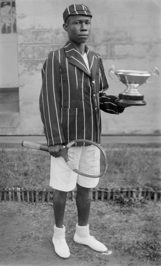 Menino com raquete de tênis e troféu