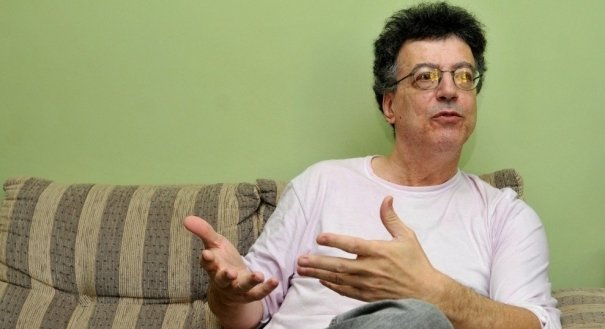 Foto do professor sentado em um sofá e justificando porque ele acha que negros não são capazes de serem médicos. imagem tirada de video