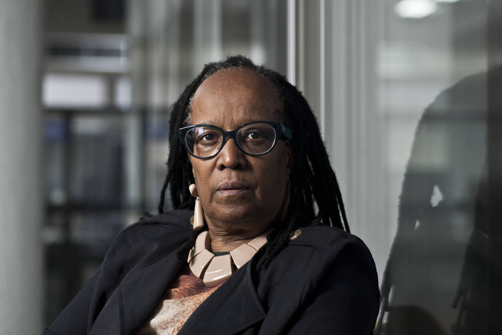 Sueli Carneiro - mulher negra, usando óculo de grau - sentada olhando para frente