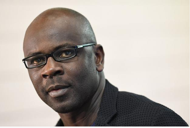 Lilian Thuram - homem negro, careca, usando óculos de grau- sentado de lado