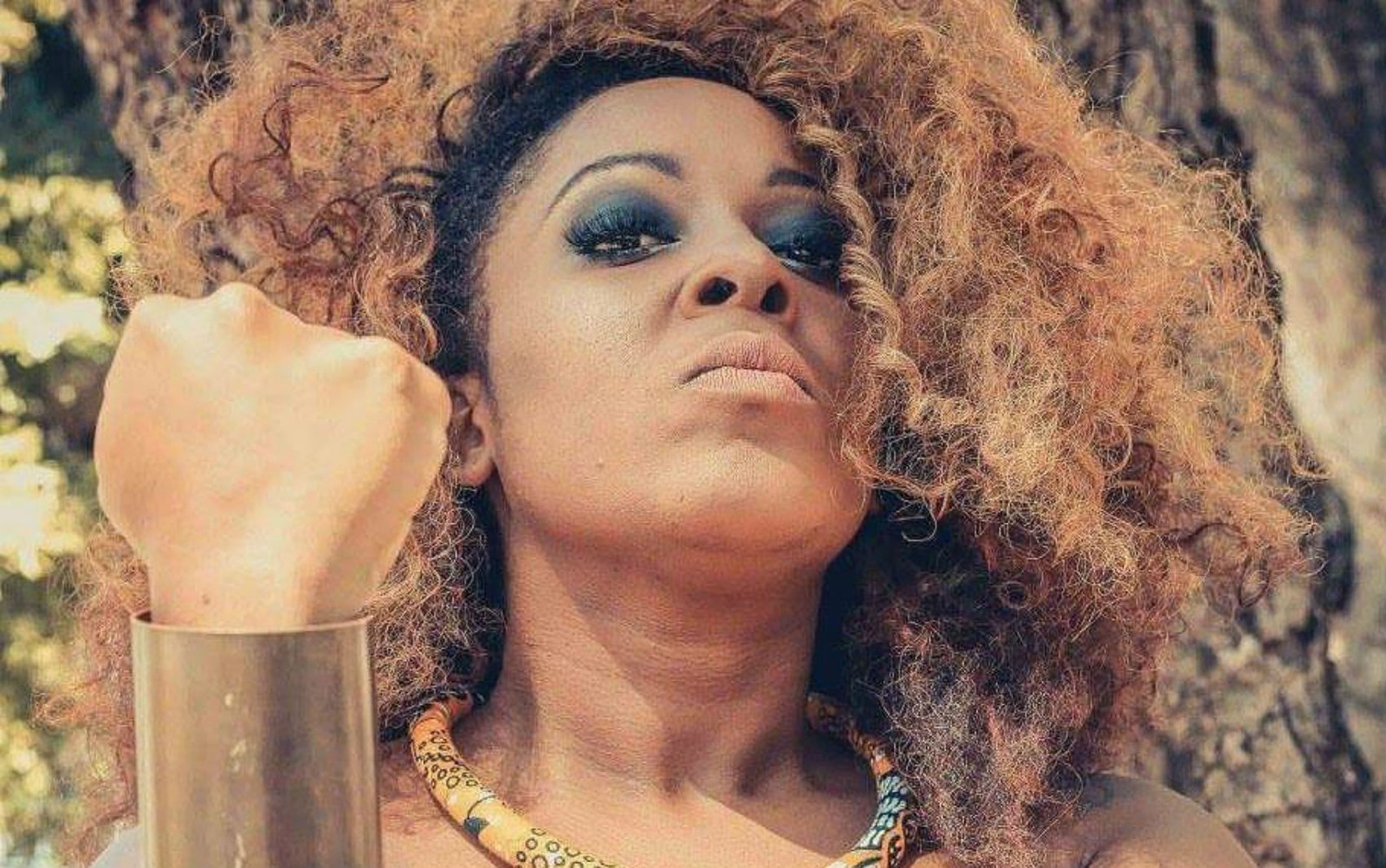 Maíra Azevedo - mulher negra de cabelo cacheado- em pé olhando para baixo