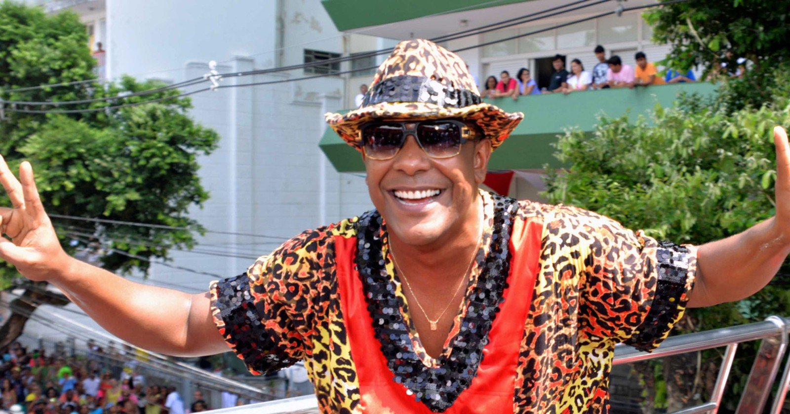 Márcio Victor - homem negro usando, óculos de sol, camiseta e chapéu colorido- em pé sorrindo
