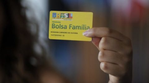 Uma mão segurando o cartão do Bolsa Família